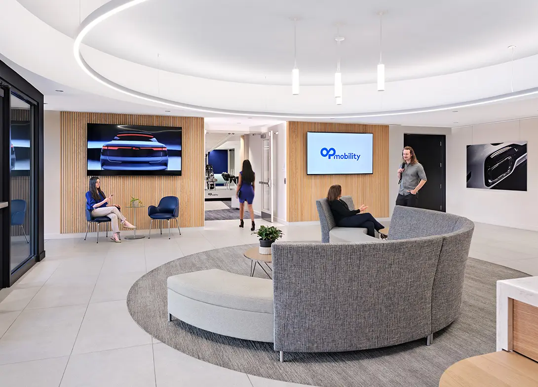 Modern office lobby with people interacting, featuring sleek design, digital displays, and OP Mobility logo.